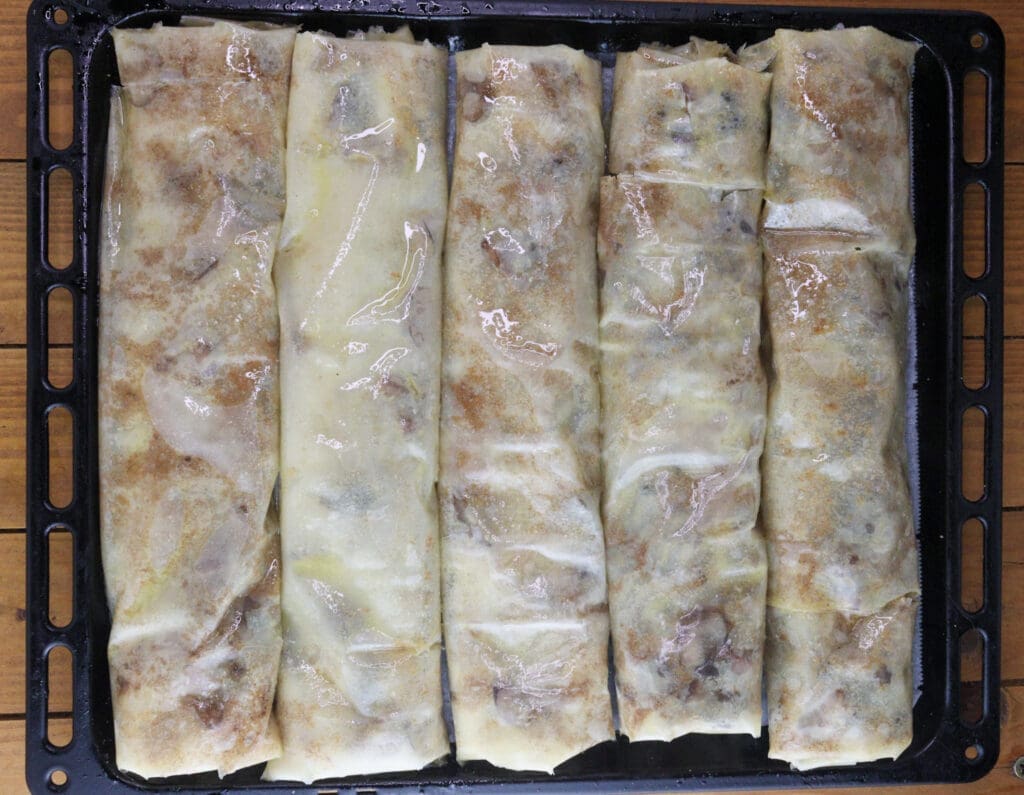 Five strudel rolls brushed with butter before baking.